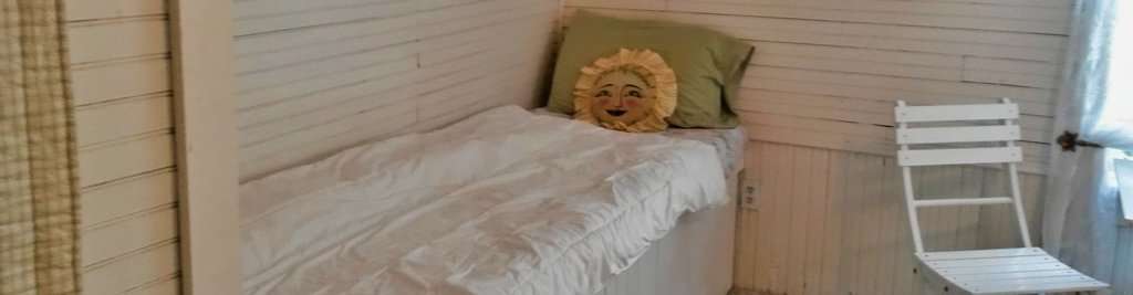 Cozy mountain harborside bedroom with white wooden walls and natural decor.